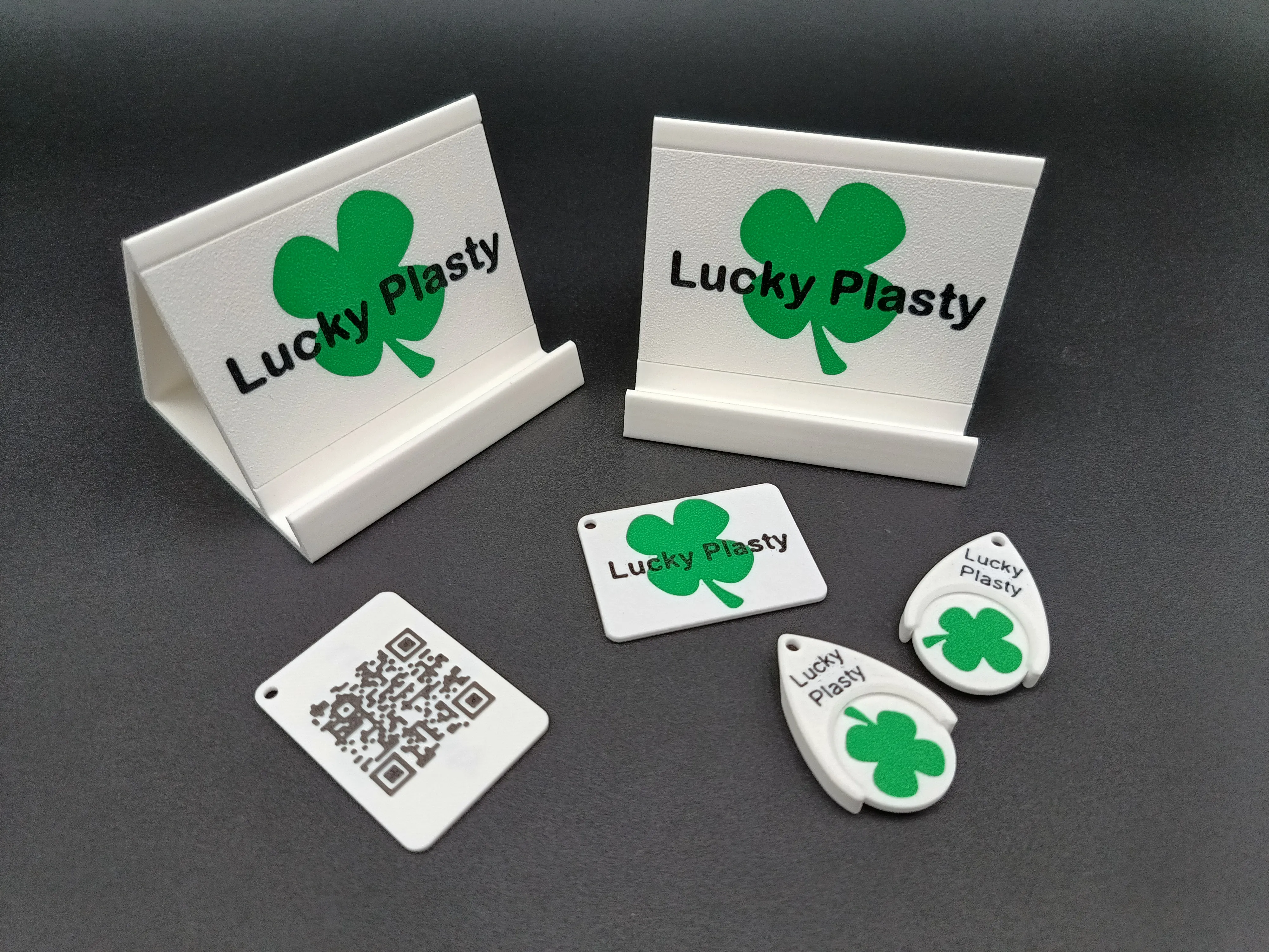 3D tištěné reklamní předměty s logem – stojánek na mobil, QR klíčenka s odkazem na web a nákupní žeton do košíku.